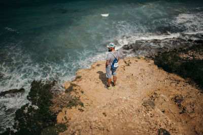 High angle view of man standing on rock at beach