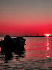 Silhouette sailboats moored in sea against sky during sunset