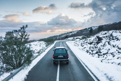 Car on road by snowcapped mountain against sky