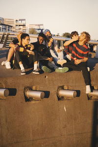 Young and teenage friends enjoying pizza at harbor in city