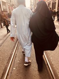 Rear view of couple walking on railroad tracks