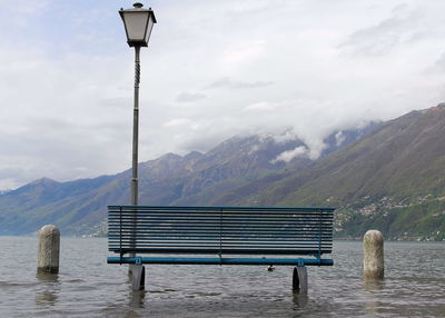 Empty bench against mountain range against sky