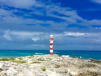 Lighthouse on beach against sky