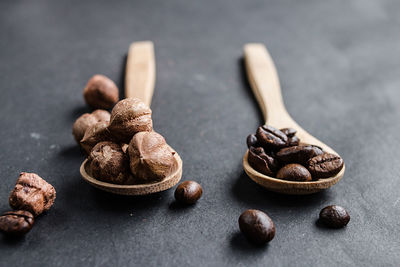 Close-up of hazelnuts with roasted coffee beans in wooden spoons on table