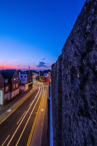 Light trails on road in city against blue sky