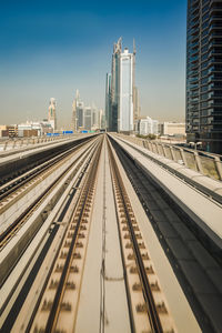 Railroad tracks in city against sky