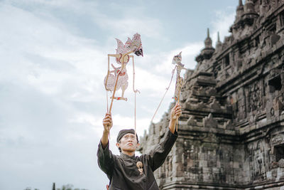 Portrait of young man with arms outstretched against the sky