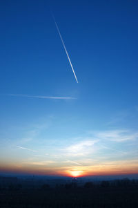 Low angle view of vapor trails in sky during sunset