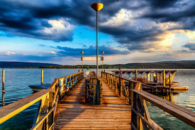 Empty jetty leading to pier at sea against sky