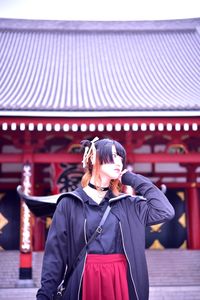 Beautiful woman looking away while standing against built structure