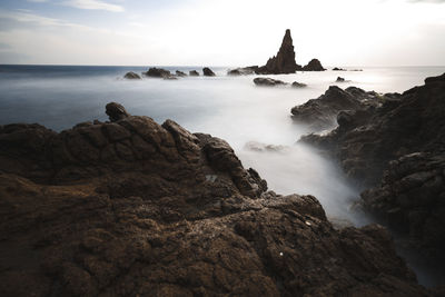 Rocks on sea shore against sky