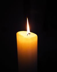 Close-up of lit tea light candle in dark room