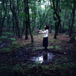 Side-view of young woman gesturing in forest