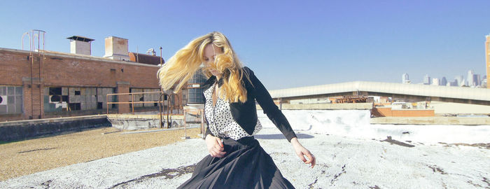 Woman standing by built structure against clear sky