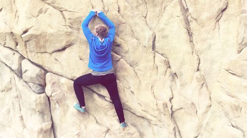 Full length rear view of man climbing rock