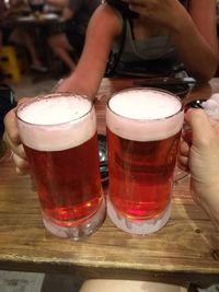 Midsection of woman holding beer glass on table