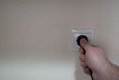 Close-up of person holding camera against wall
