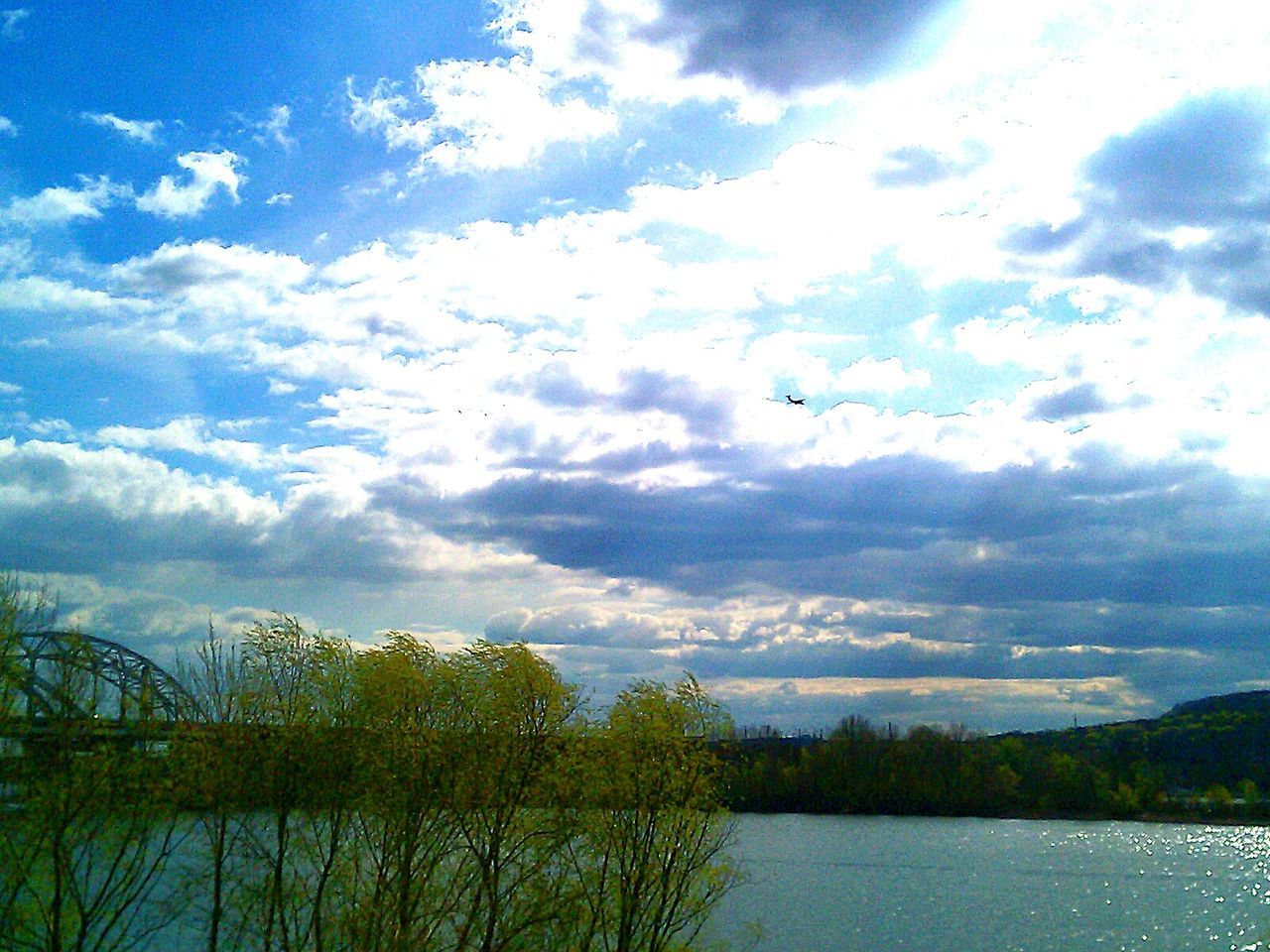 sky, cloud - sky, water, tree, tranquil scene, scenics, tranquility, transportation, lake, flying, cloud, nature, beauty in nature, cloudy, waterfront, mode of transport, river, blue, mid-air, day