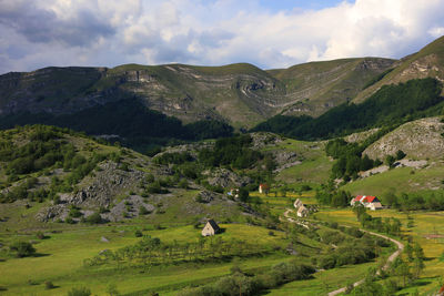 Scenic view of green landscape and mountains against sky