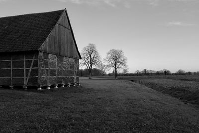 Barn on field by building against sky