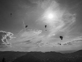 Hot air balloons flying over silhouette mountains against sky