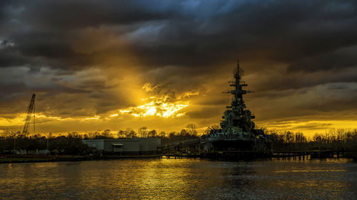 Scenic view of river by buildings against sky during sunset