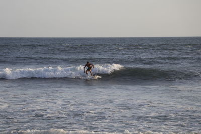 Man surfing in sea against sky