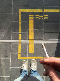 Low section of man smoking cigarette on footpath