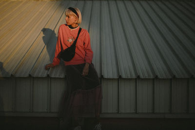 Full length of woman standing against wall