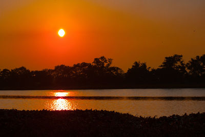 Scenic view of lake against orange sky