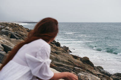 Rear view of woman looking at sea against clear sky