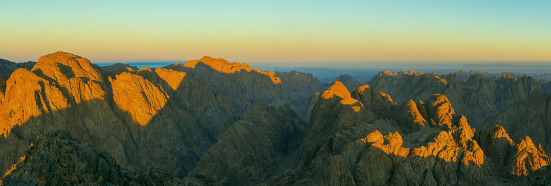 Panoramic view of rocks and mountains against sky during sunset