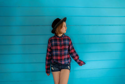 Young woman looking away against blue wall