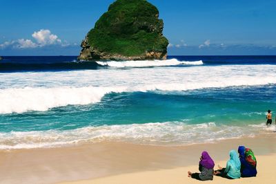Rear view of people at beach against sky