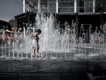 Full length of woman standing on fountain