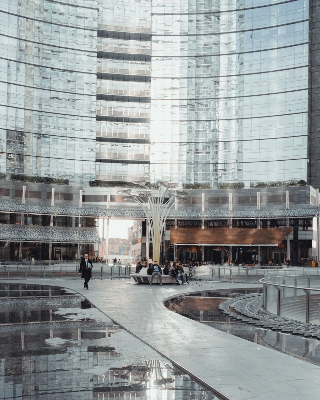 REFLECTION OF PEOPLE ON GLASS BUILDING