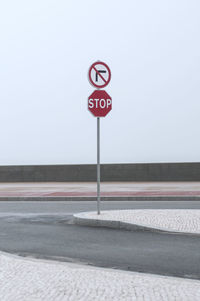 Road sign on street against clear sky