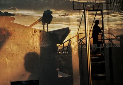 Silhouette of man working on wet railing