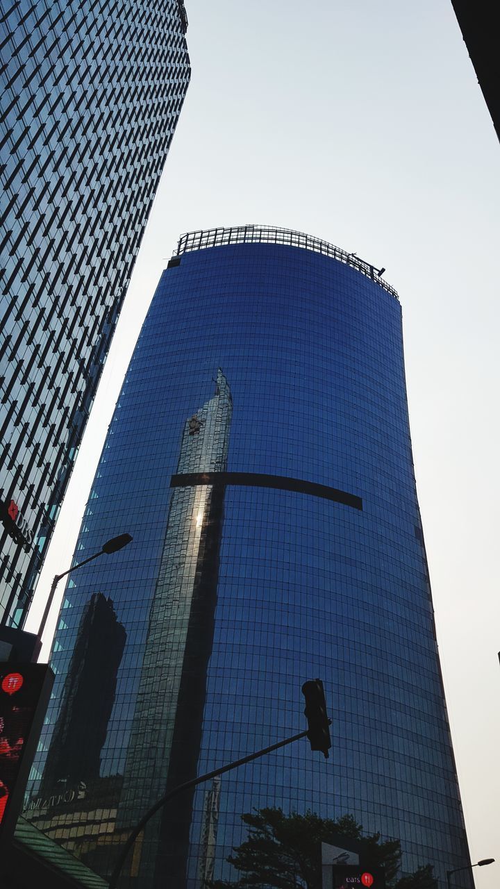 LOW ANGLE VIEW OF MODERN GLASS BUILDING AGAINST SKY