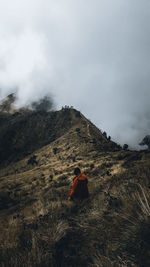 Rear view of woman standing on mountain against sky