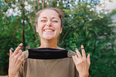 Happy girl takes off protective medical mask from face outdoors. young woman  after vaccination