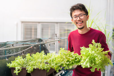 Portrait of smiling young man by potted plant