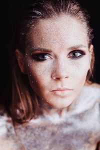 Close-up portrait of beautiful young woman over black background