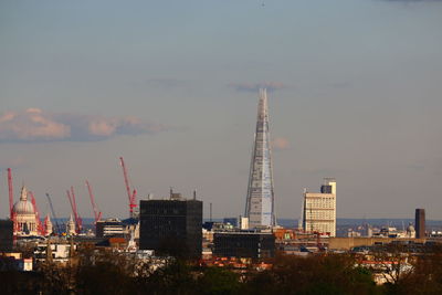 Cranes at construction site within city against sky