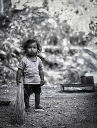 Cute girl holding broom while standing outdoors