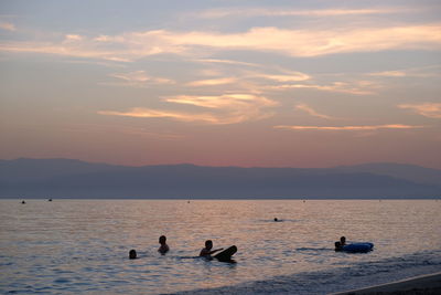 Silhouette ducks swimming in sea against sky during sunset