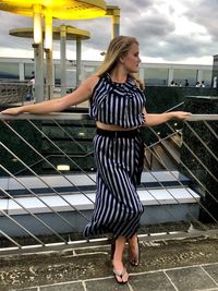 Full length of woman standing on railing against sky