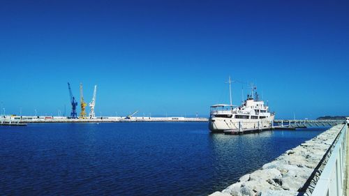 Commercial dock by sea against clear blue sky