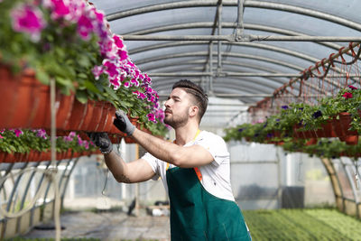 Midsection of man holding flower in greenhouse