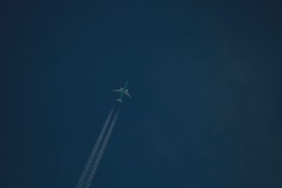 Low angle view of airplane flying against clear blue sky